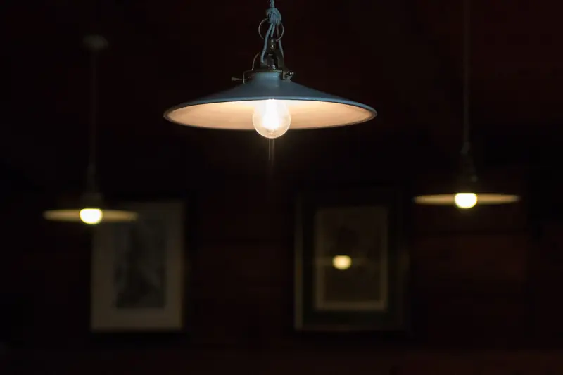 Metal pendant lamps hang low and glow warmly over a dim dining room