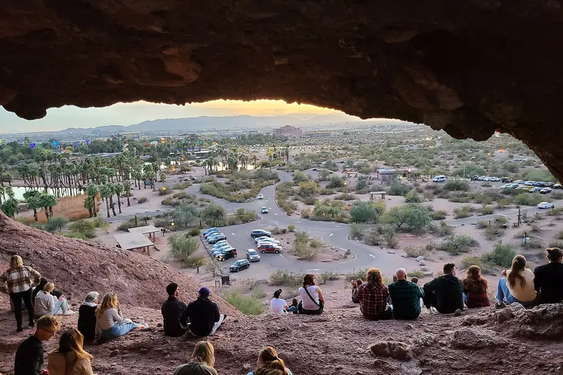 View from inside Hole-in-the-Rock at Papago Park, looking out over Phoenix as visitors sit on the red rock