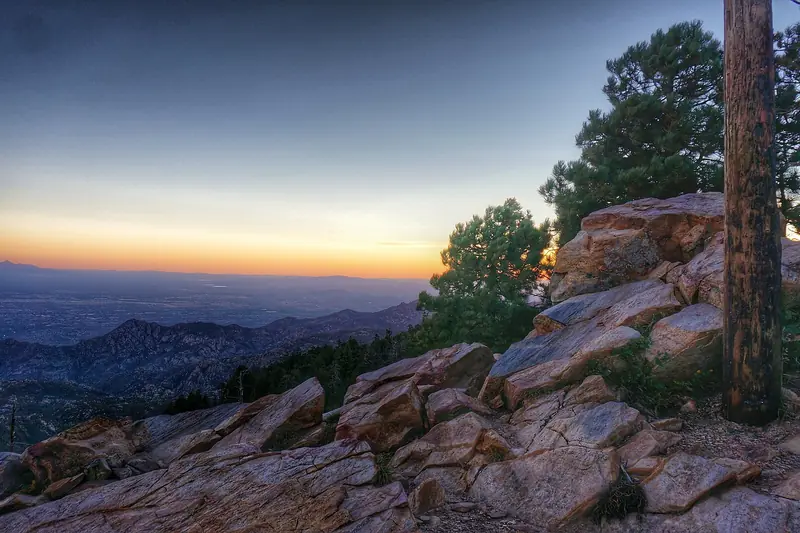 Sunset glows over the Tucson valley seen from the rocky, pine-dotted slopes of Mount Lemmon, Arizona